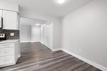 an empty kitchen and living room with white walls and wood flooring